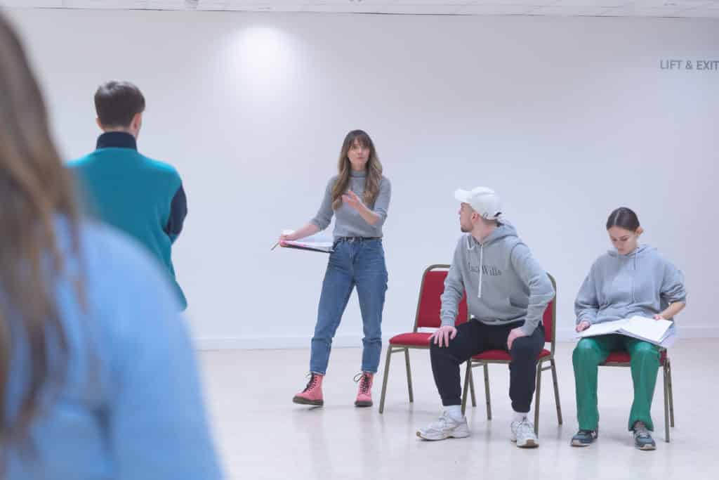 Acting class rehearsals with different students in a white room with some students sitting on chairs